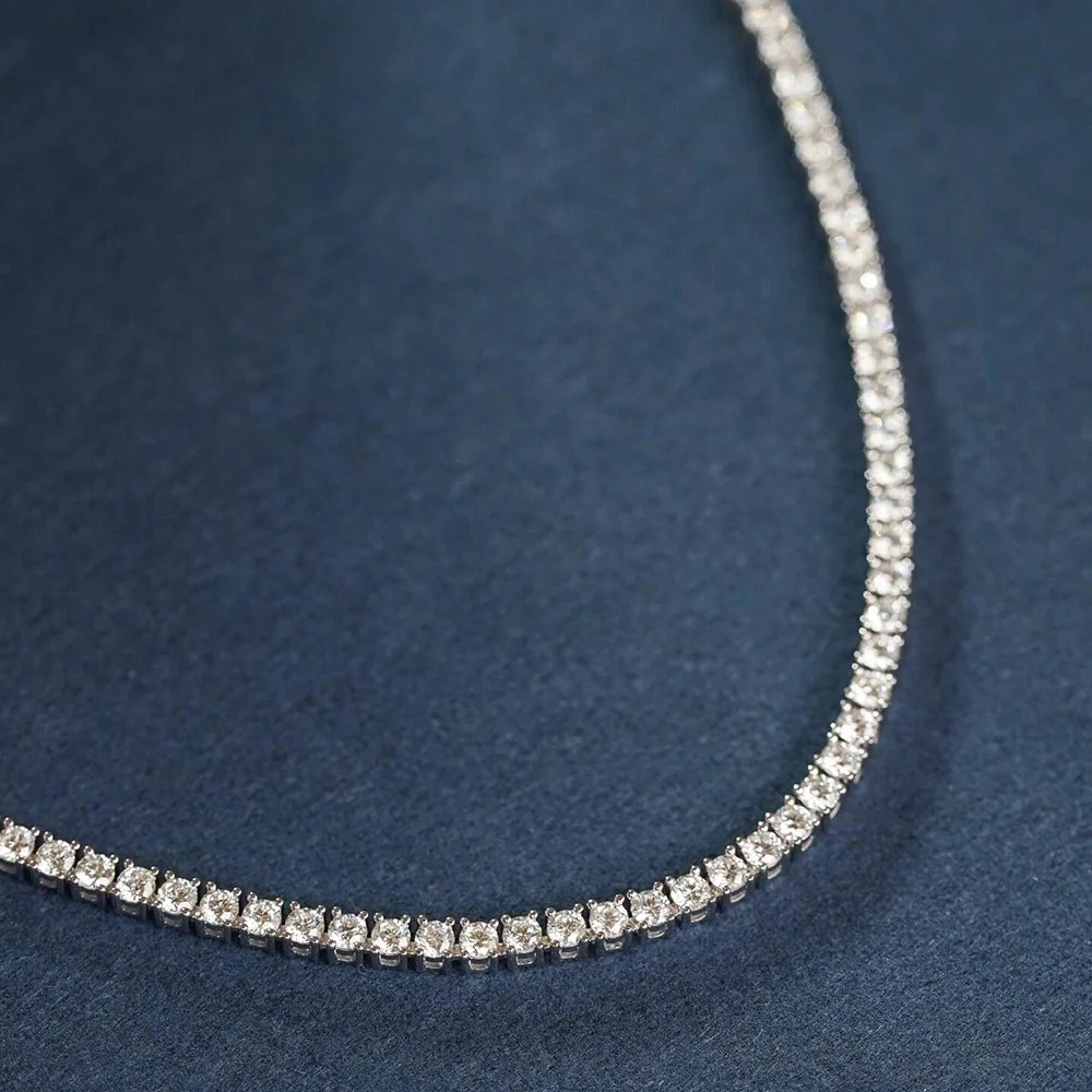 Close up detail of 3mm round brilliant moissanite stones in 4-prong setting on silver tennis chain