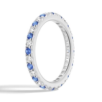Perspective side angle view of alternating blue and white sapphire eternity band in white gold