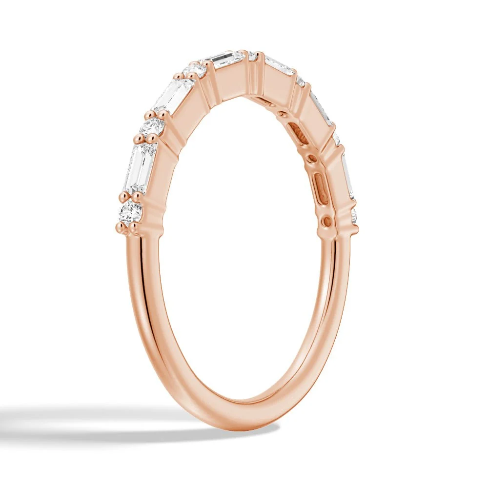Three-quarter perspective view of baguette and round moissanite wedding band in rose gold