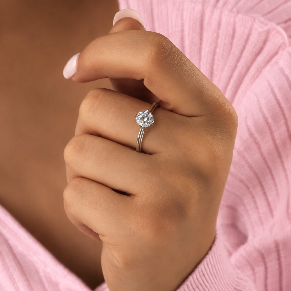 Model wearing classic four prong round moissanite solitaire engagement ring on finger