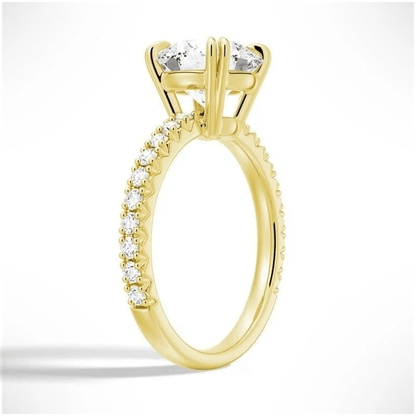 Angled view of Classic Round Moissanite Solitaire Engagement Ring 4 Prong with Pave Band in Yellow Gold - Novelle Vow