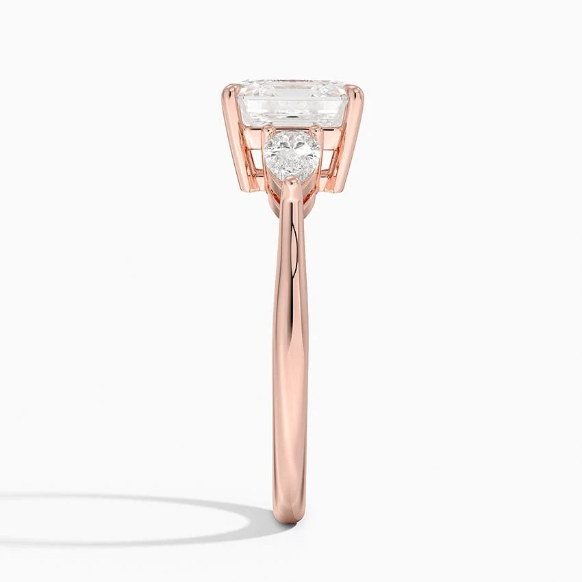 Rose gold classic three-stone asscher cut moissanite engagement ring direct side profile view showing prong set pear accents