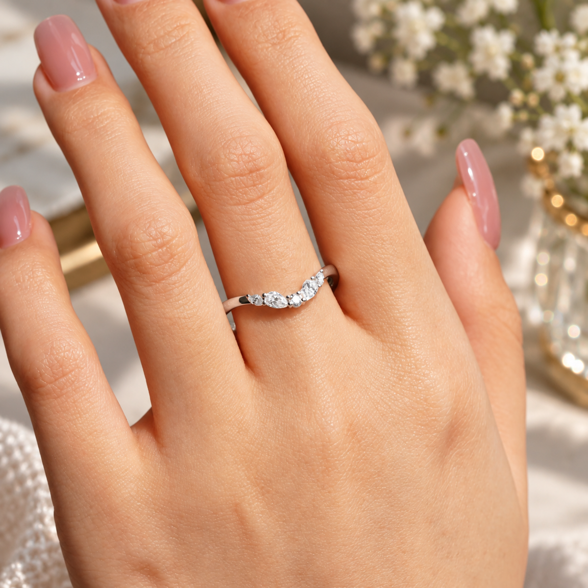 White gold curved multi-shape moissanite wedding band worn on female hand