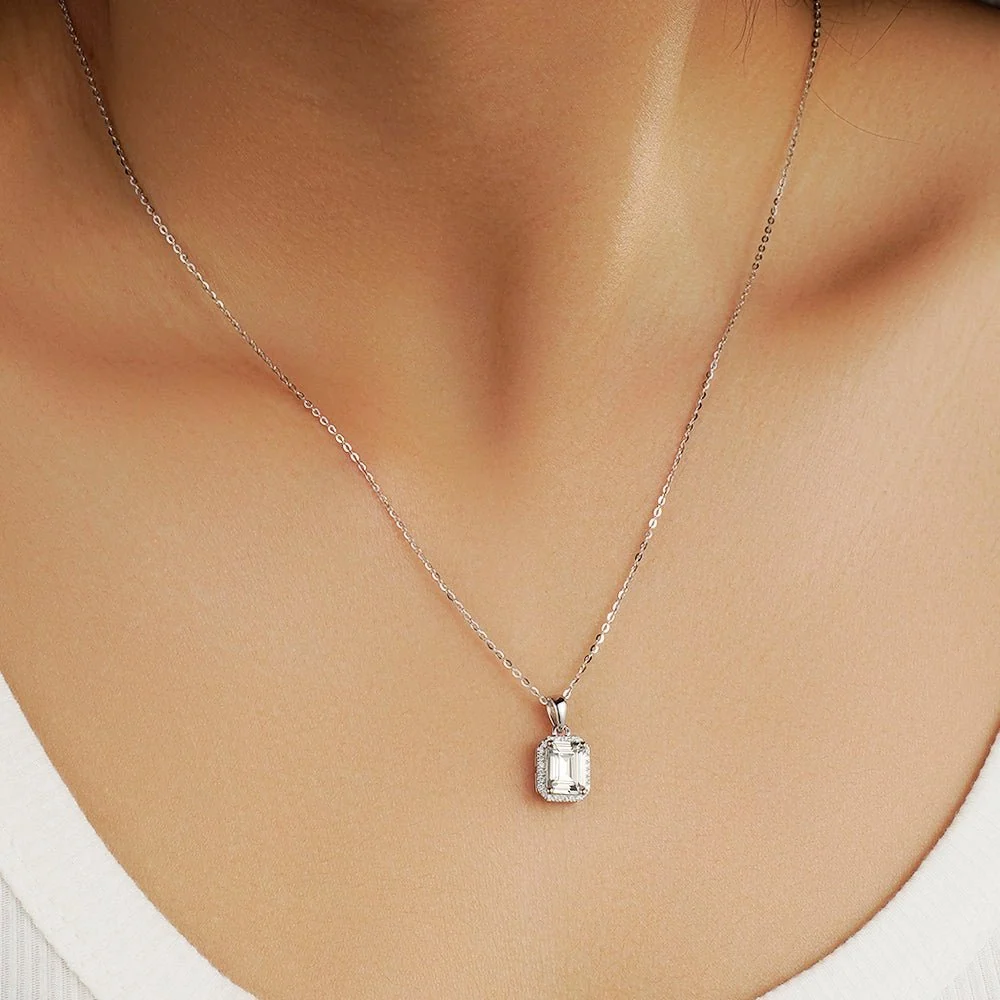 Emerald cut moissanite halo pendant necklace worn on model collarbone front view