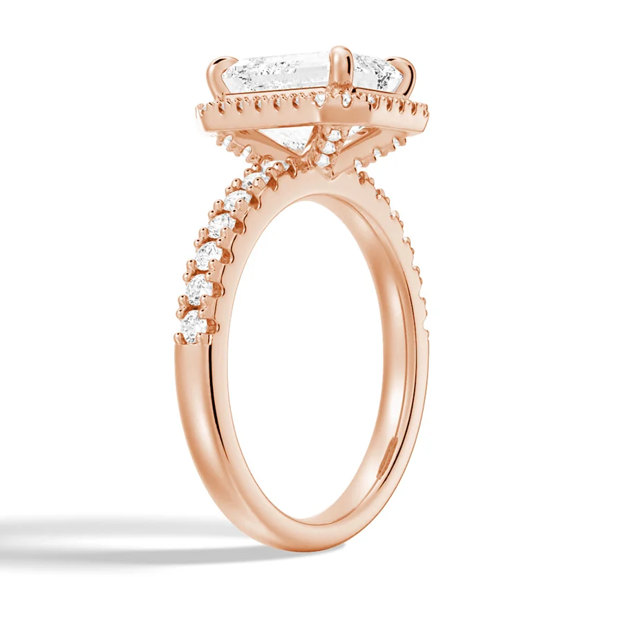 Rose gold emerald cut moissanite engagement ring 3/4 side angle view showing halo basket