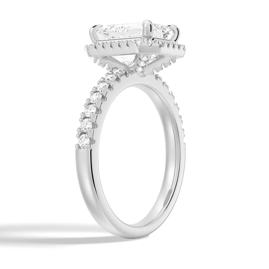 White gold emerald cut moissanite engagement ring 3/4 side angle view showing halo basket