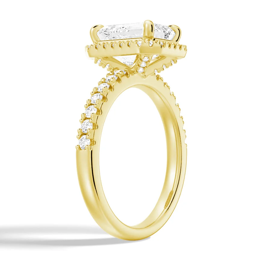 Yellow gold emerald cut moissanite engagement ring 3/4 side angle view showing halo basket