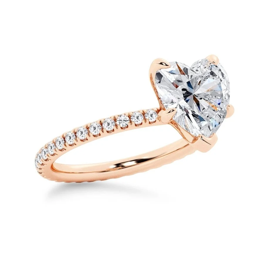 Rose gold heart shaped moissanite engagement ring side profile perspective view showing three prong basket