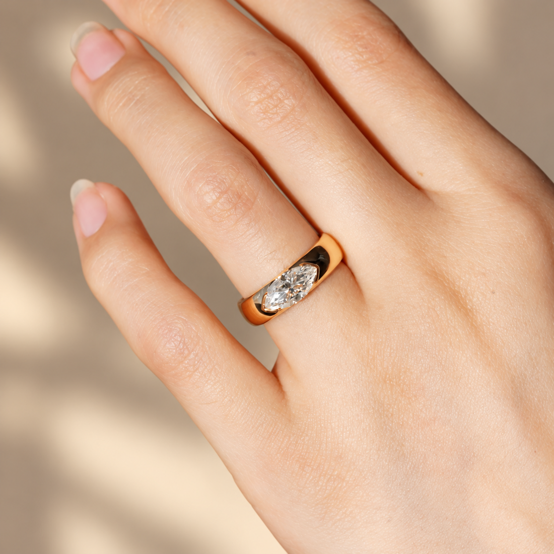 Rose gold marquise cut moissanite east-west half bezel solitaire ring worn on model finger