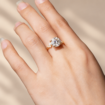 On-hand view of yellow gold round moissanite engagement ring with marquise leaf detail