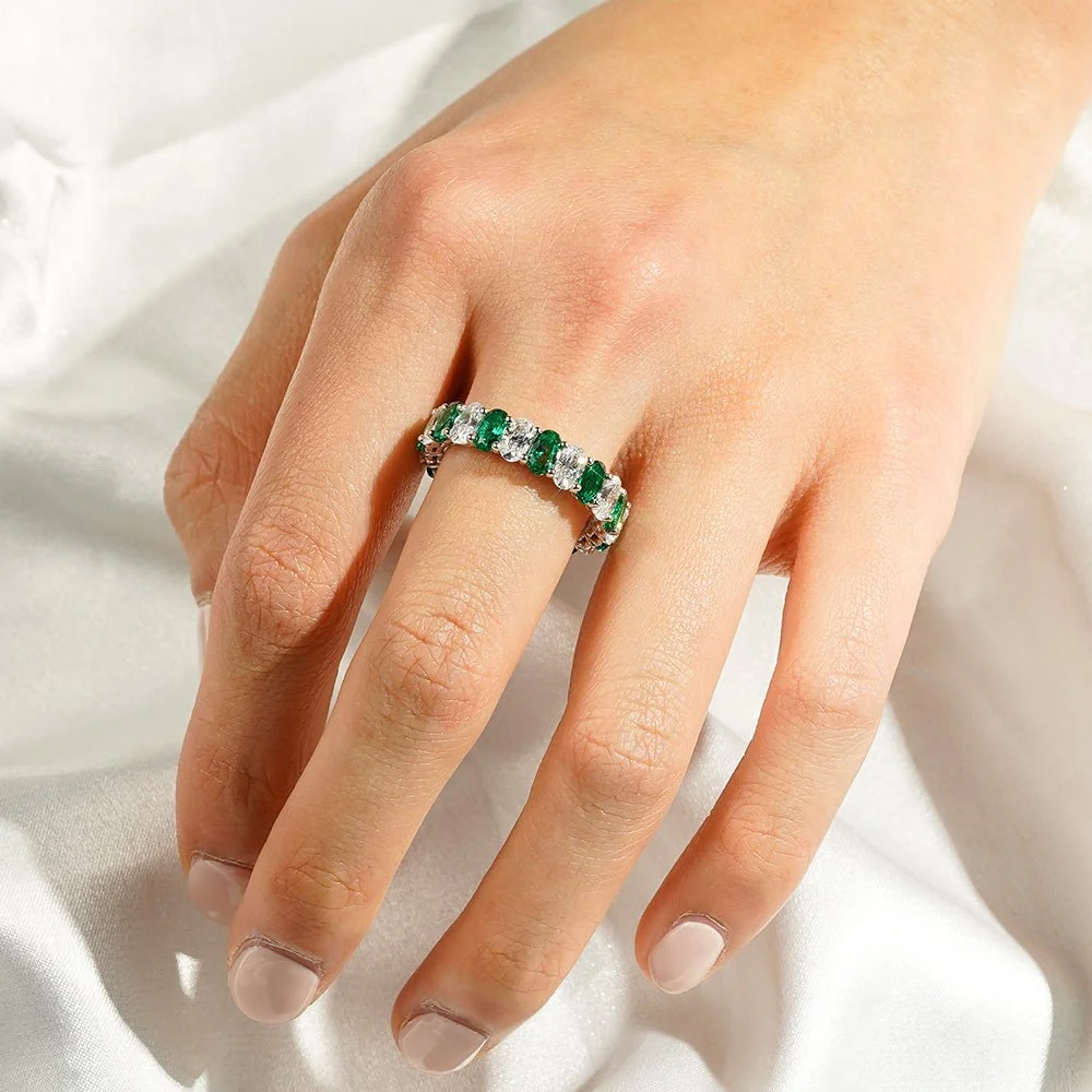 Full hand perspective of alternating emerald and white sapphire eternity band worn on finger