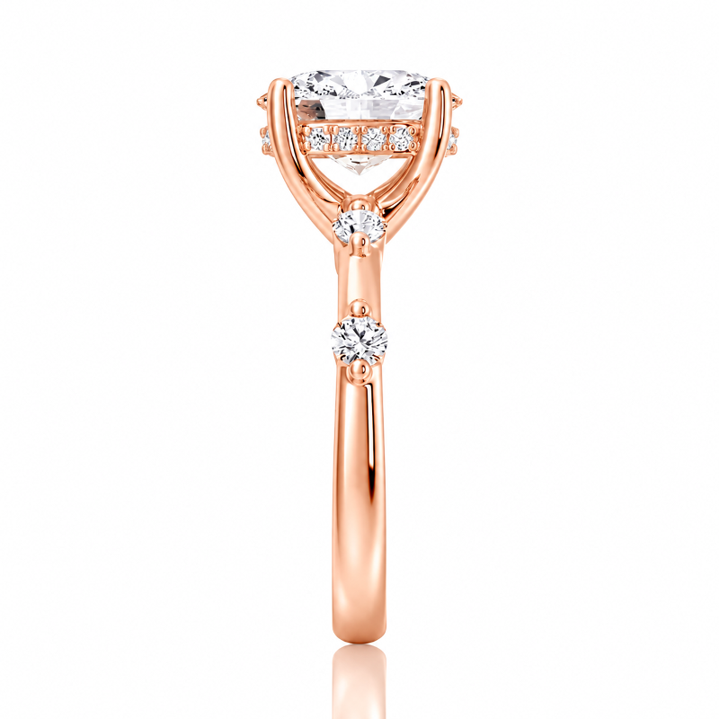 Rose gold oval moissanite ring side view displaying spaced accent stones along the bandRose gold oval moissanite ring side view displaying spaced accent stones along the band