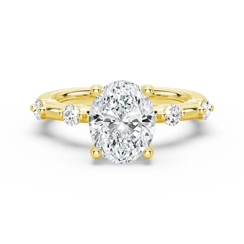 Yellow gold oval moissanite engagement ring top view with spaced accent stones on 1.5mm band