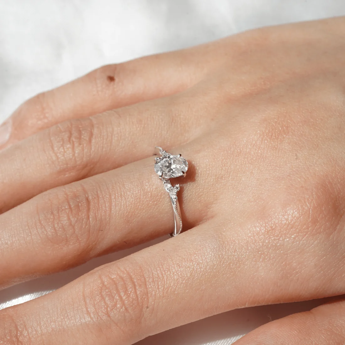 Model hand wearing white gold nature inspired oval moissanite engagement ring