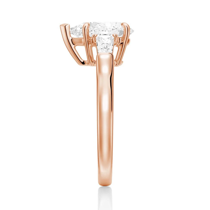 Rose gold pear moissanite engagement ring direct side view showing basket setting and tapered baguettes