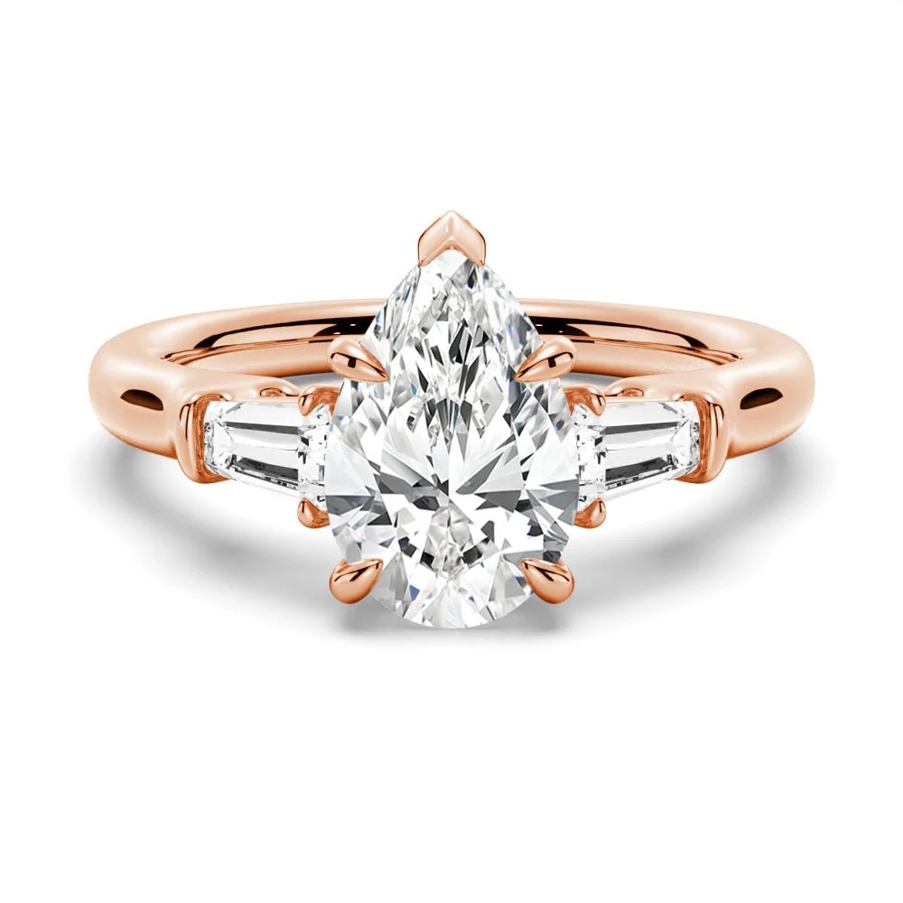 Rose gold pear moissanite engagement ring top view with tapered baguette side stones and double claw prongs