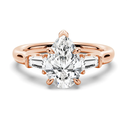 Rose gold pear moissanite engagement ring top view with tapered baguette side stones and double claw prongs