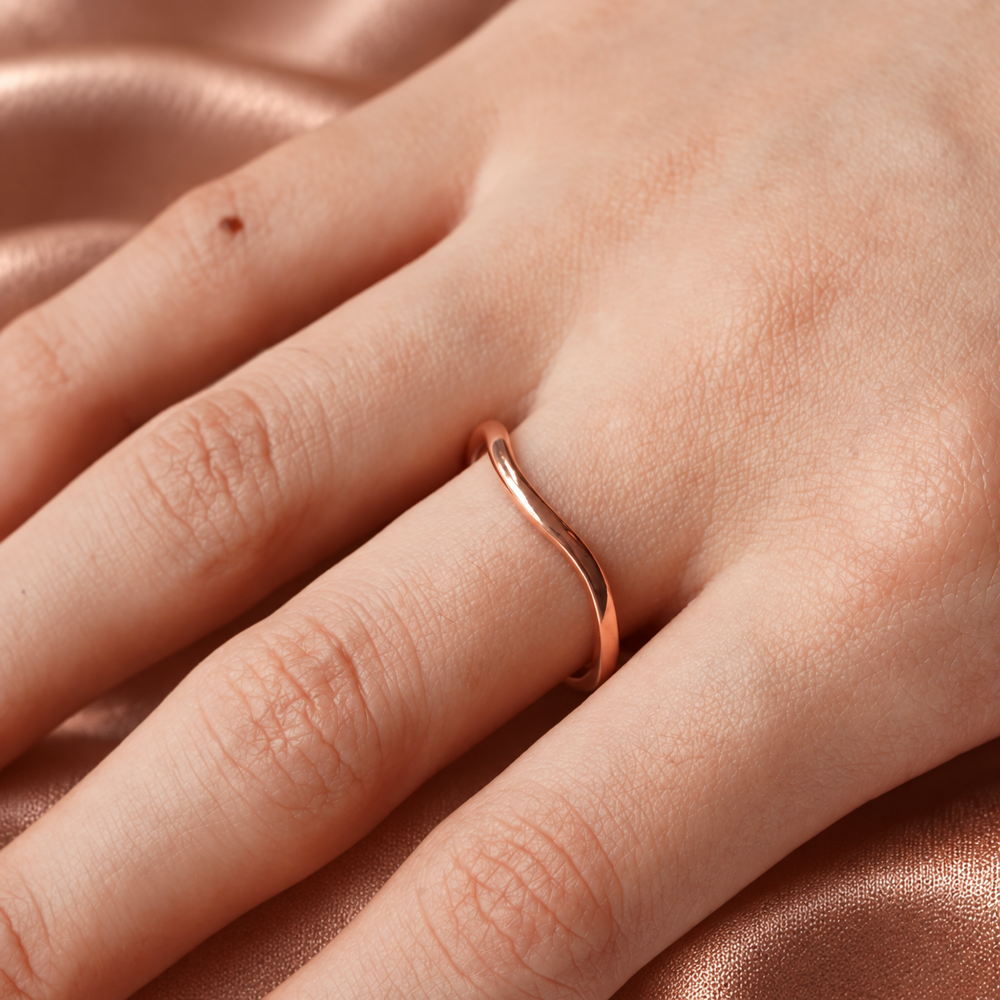 On-finger view of 1.6mm rose gold plain curved matching band on silk backdrop