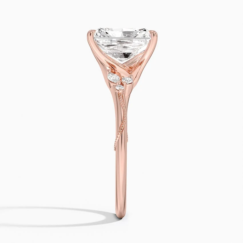 Rose gold radiant cut moissanite engagement ring direct side profile view showing milgrain vine band and cluster side accents
