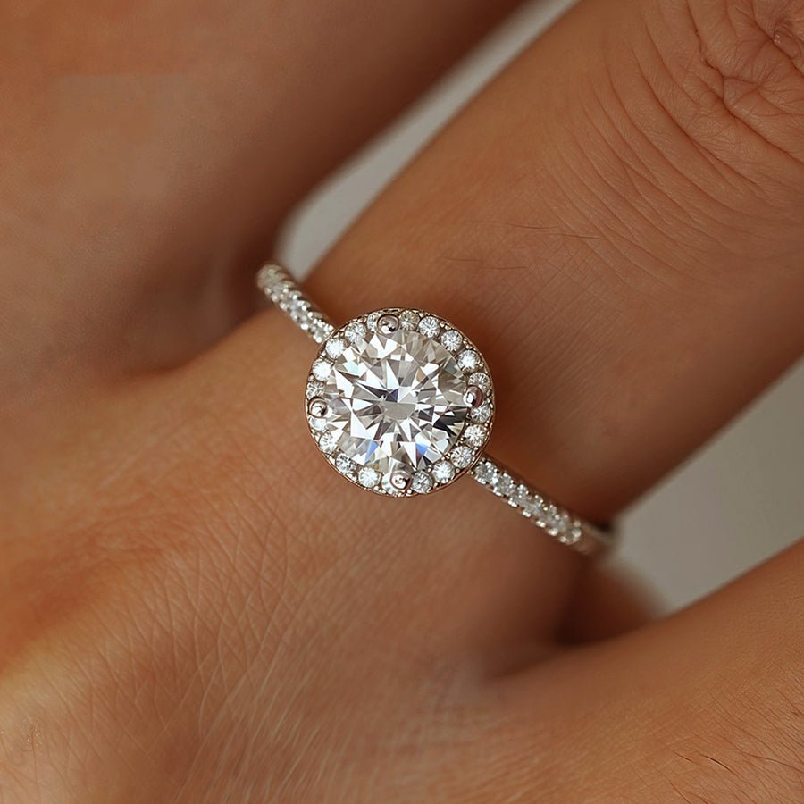 Close-up on hand of Radiant Round Cut Moissanite Halo Engagement Ring in White Gold - Novelle Vow