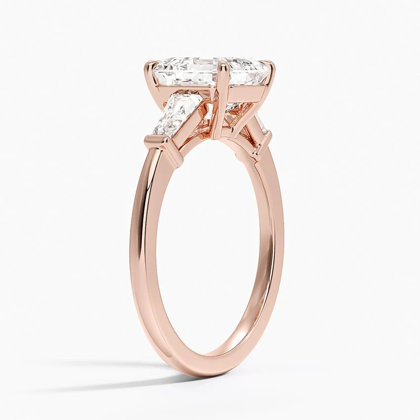 Rose gold asscher cut moissanite three-stone engagement ring 3/4 side perspective view showing claw prongs