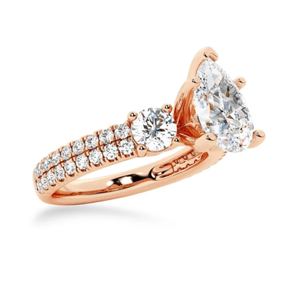 Rose gold three stone pear moissanite engagement ring 3/4 angle view showcasing side accent gems