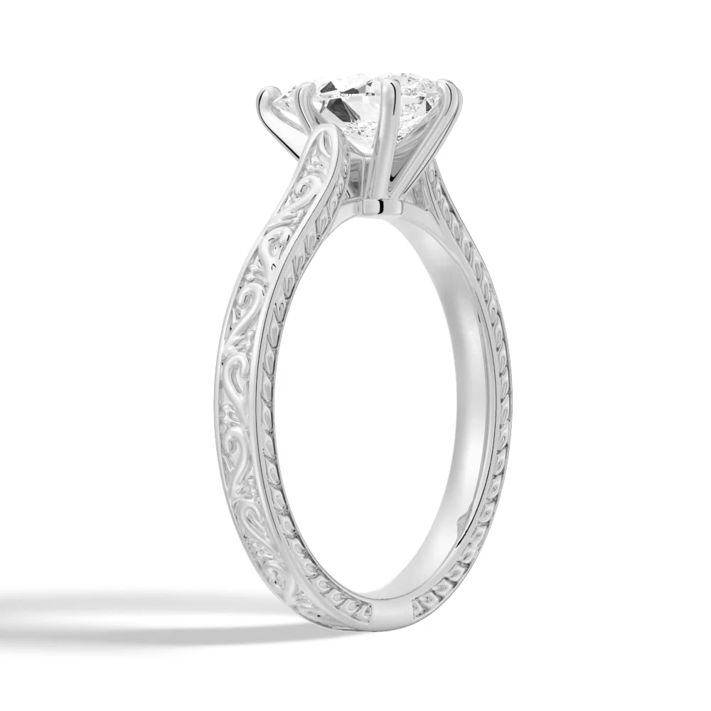 White gold vintage pear-cut moissanite engagement ring 3/4 perspective view showcasing scrollwork engraving