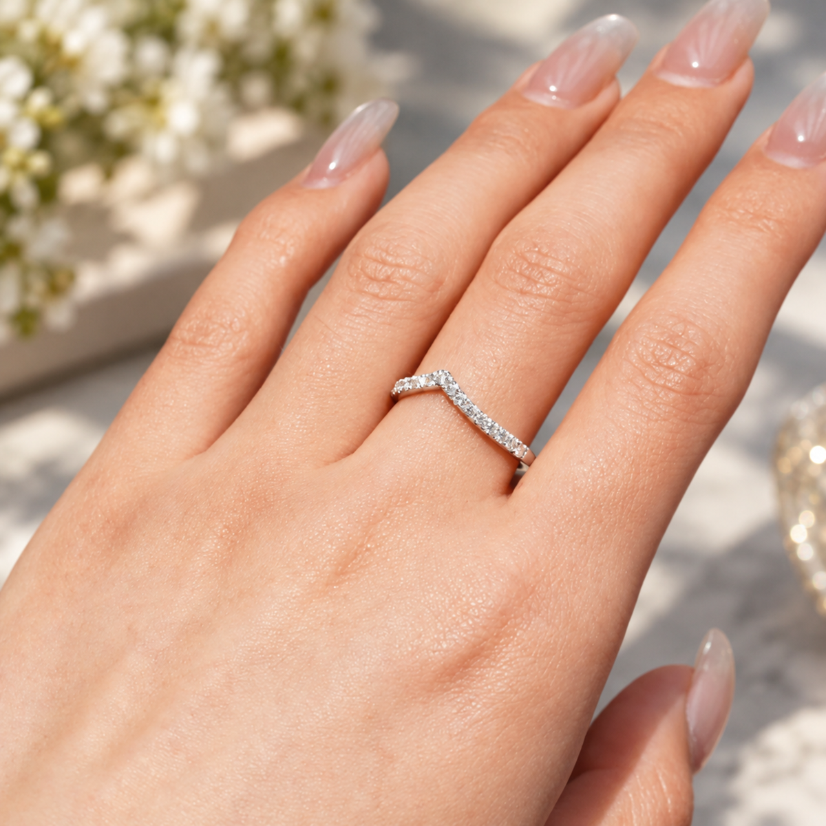 On-hand view of 0.28ct TW curved V-shaped moissanite French pavé wedding band worn on finger