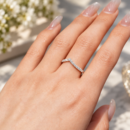 On-hand view of 0.28ct TW curved V-shaped moissanite French pavé wedding band worn on finger