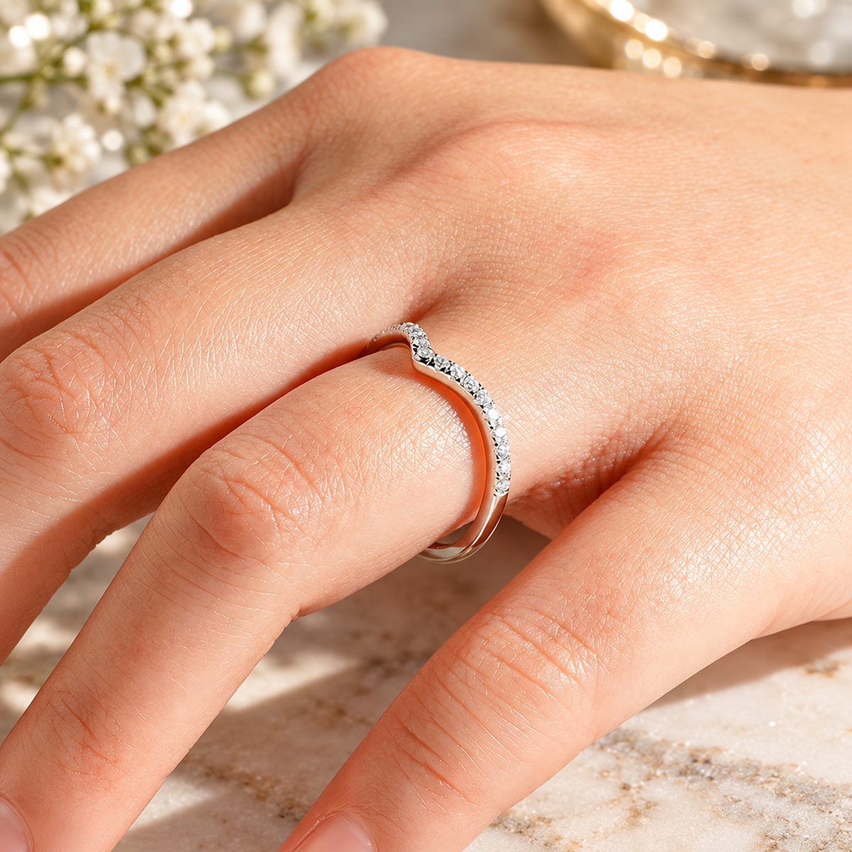 Close-up on-hand view of 0.28ct TW curved V-shaped French pavé moissanite wedding band in white gold color